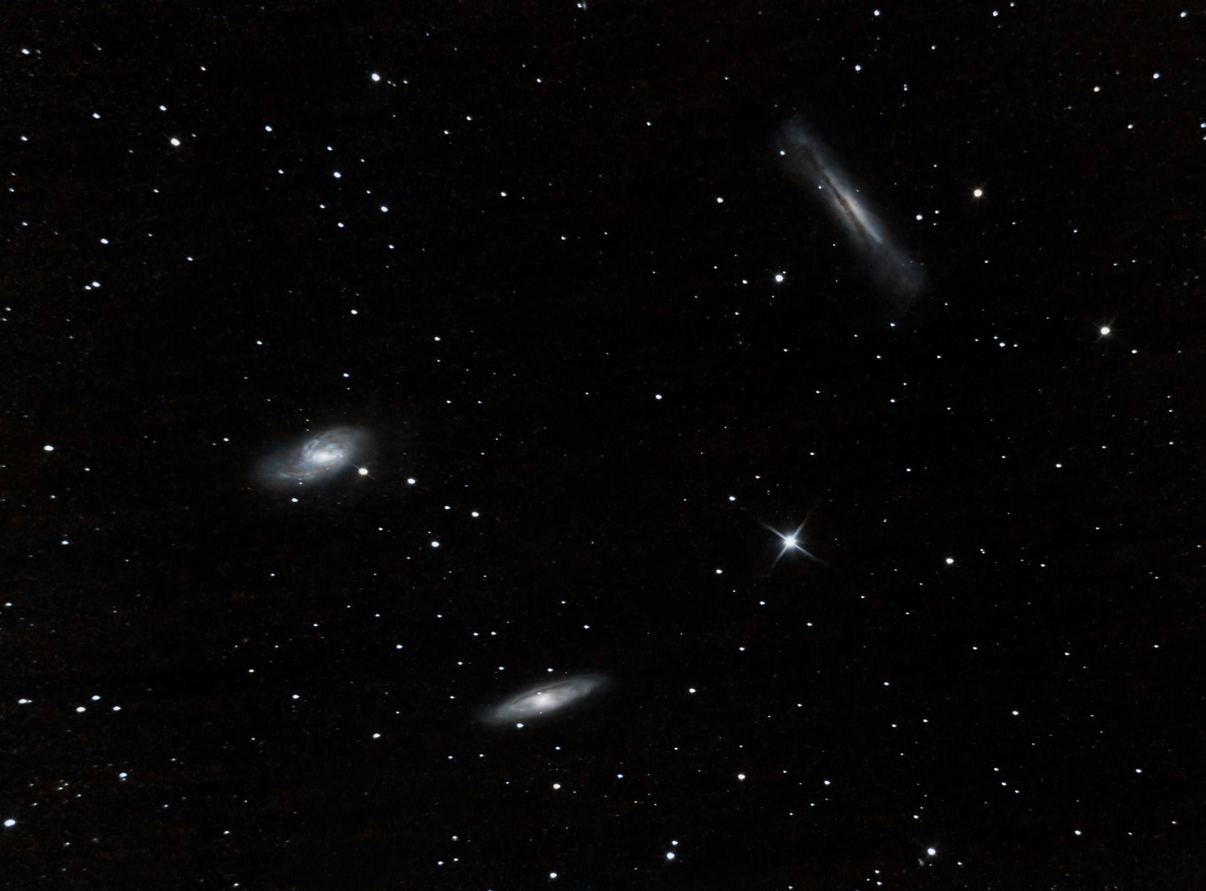 Three small galaxies of the Leo Triplet scattered across a field of stars.